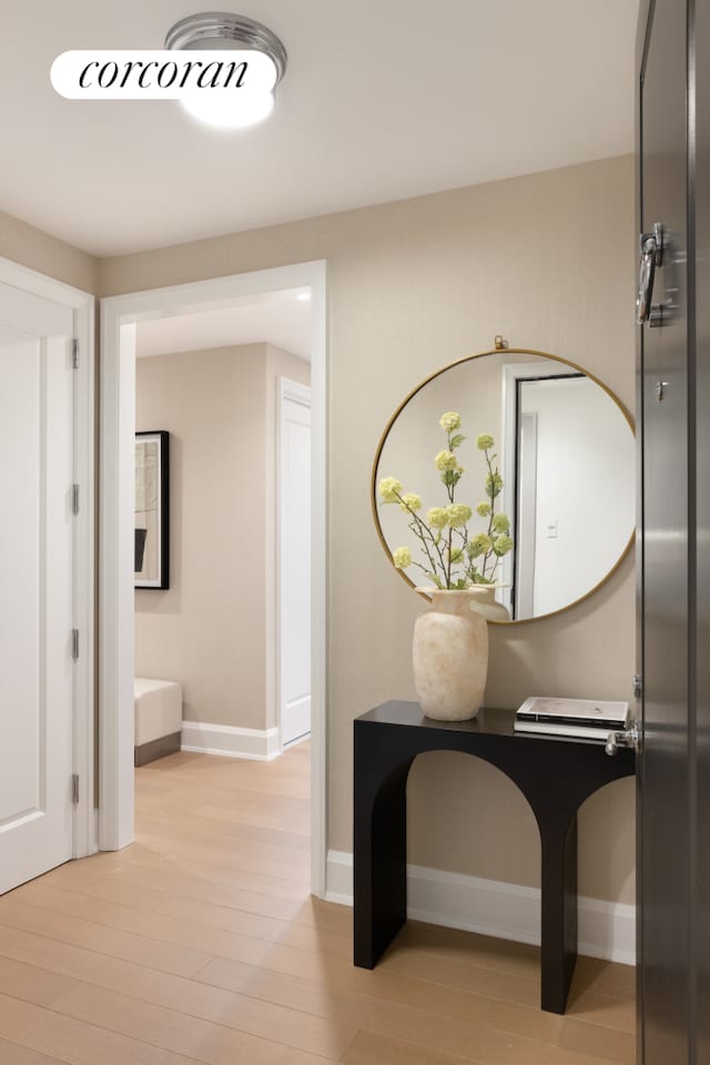 corridor featuring light wood finished floors, visible vents, and baseboards