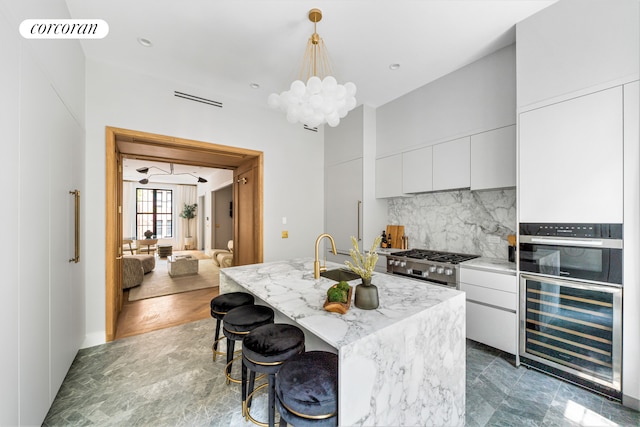 kitchen with beverage cooler, visible vents, white cabinetry, decorative backsplash, and an inviting chandelier