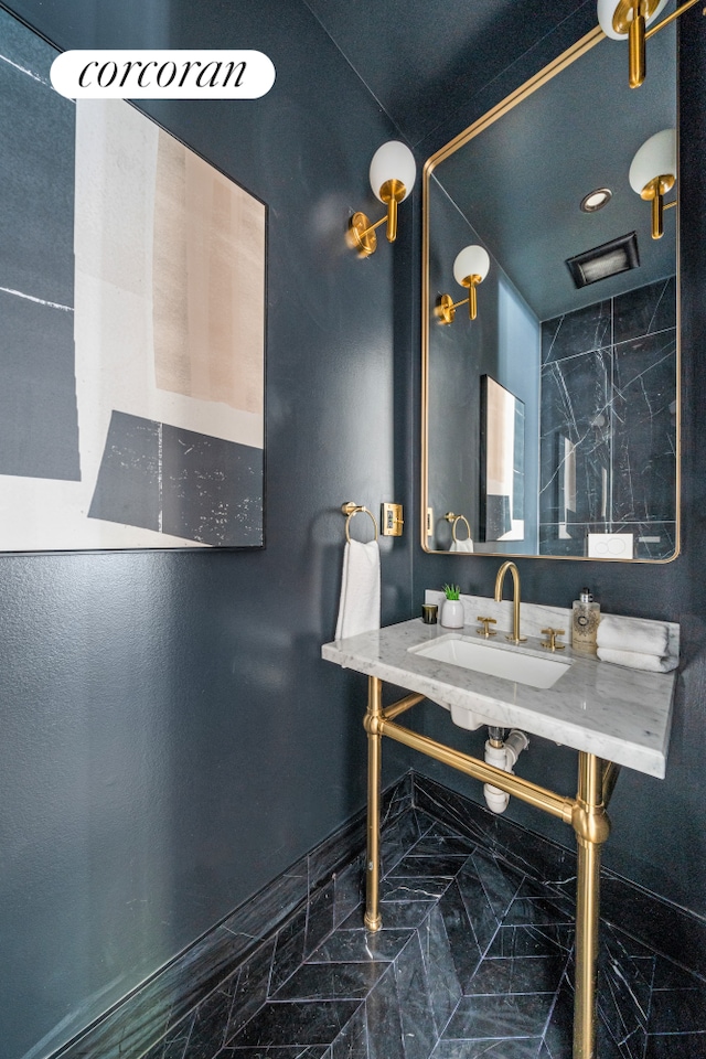 bathroom featuring marble finish floor, a sink, and baseboards