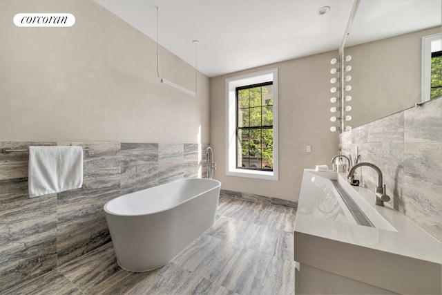 full bathroom featuring visible vents, a soaking tub, vanity, and tile walls