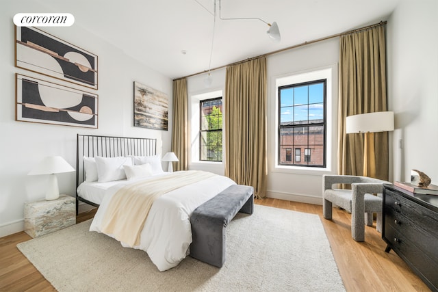 bedroom with light wood finished floors, visible vents, and baseboards