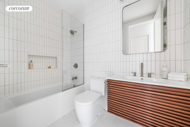 full bathroom featuring tile walls, bathing tub / shower combination, toilet, vanity, and tile patterned flooring