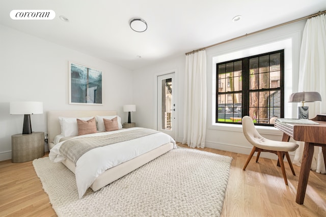 bedroom with light wood-style floors, baseboards, visible vents, and access to outside