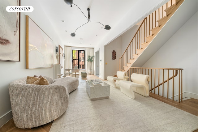 living room featuring stairs, baseboards, and wood finished floors