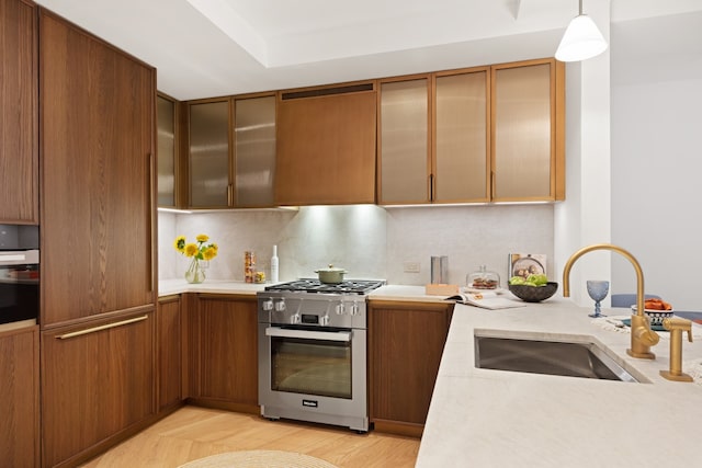 kitchen featuring sink, backsplash, stainless steel range with gas stovetop, wall oven, and hanging light fixtures