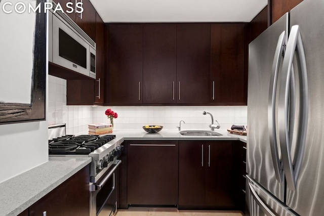 kitchen featuring a sink, stainless steel appliances, backsplash, and dark brown cabinetry