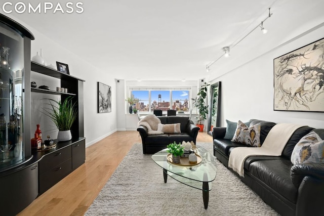 living area with rail lighting, baseboards, and light wood-type flooring