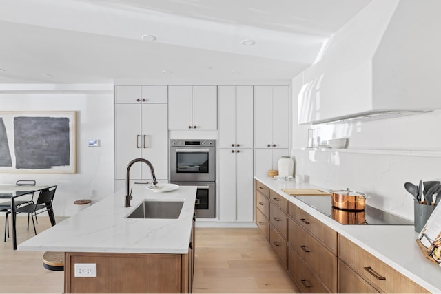 134 Weirfield St Unit 2, New York City, NY 11221 - kitchen with a sink, stainless steel double oven, light wood-style floors, black electric stovetop, and light stone counters
