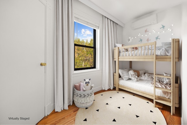 bedroom with a wall unit AC and wood finished floors