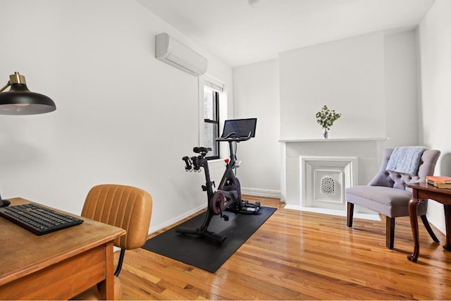 exercise room featuring light hardwood / wood-style floors and an AC wall unit