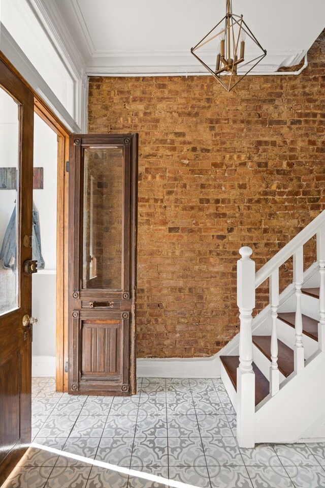 interior space featuring crown molding, light tile patterned flooring, a chandelier, and brick wall