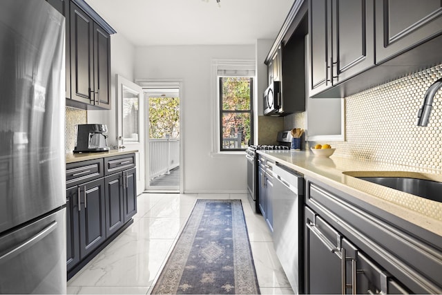 kitchen featuring marble finish floor, stainless steel appliances, a sink, and light countertops