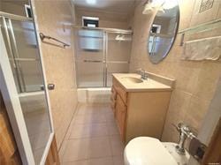 full bath featuring toilet, a stall shower, tile patterned flooring, and vanity