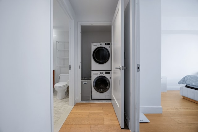 laundry area with stacked washing maching and dryer and light hardwood / wood-style floors