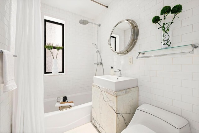 bathroom featuring tile walls, a sink, toilet, and shower / tub combo with curtain