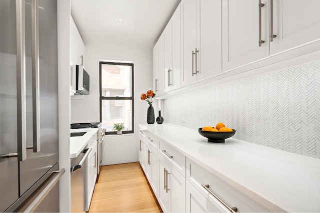 kitchen featuring appliances with stainless steel finishes, light wood-style flooring, and white cabinets