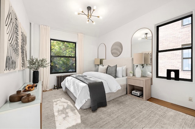 bedroom featuring a chandelier, radiator, and wood finished floors