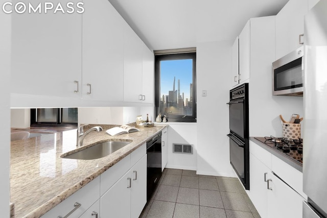 kitchen with white cabinets, light stone countertops, sink, and black appliances