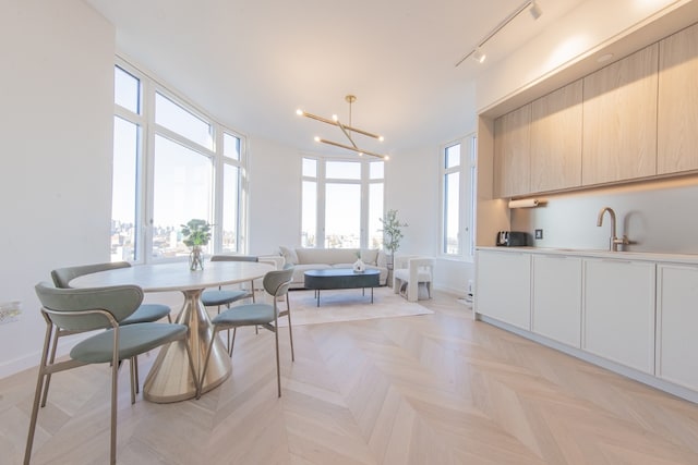 dining room featuring light parquet floors, plenty of natural light, sink, and a chandelier