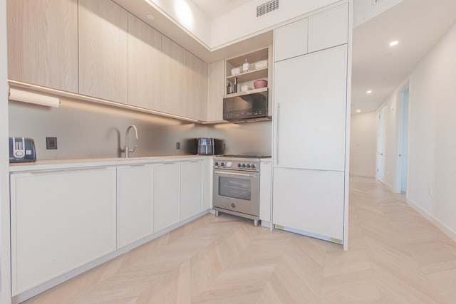 kitchen featuring recessed lighting, visible vents, light countertops, high end stainless steel range oven, and modern cabinets