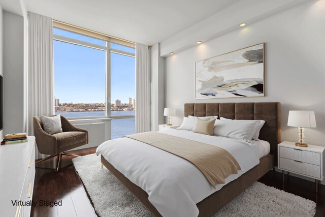 bedroom with a water view, expansive windows, and dark wood-style flooring