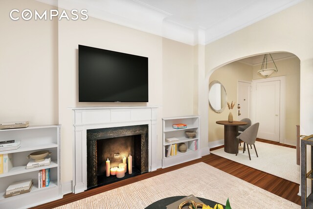 living area featuring baseboards, a premium fireplace, wood finished floors, and crown molding