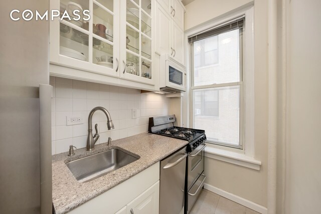 kitchen featuring appliances with stainless steel finishes, white cabinetry, sink, decorative backsplash, and a healthy amount of sunlight