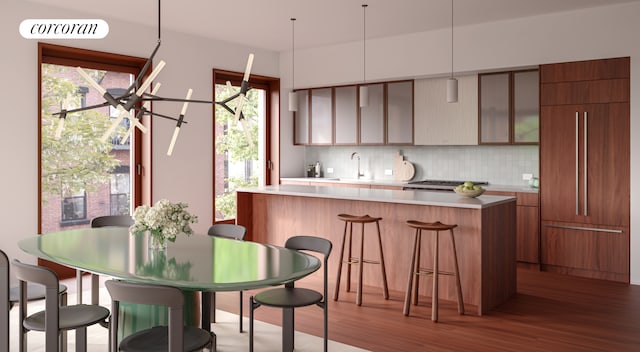 kitchen with wood finished floors, a breakfast bar, light countertops, backsplash, and modern cabinets