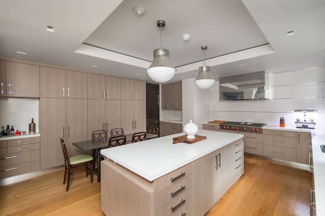 kitchen with range hood, a raised ceiling, light wood finished floors, and a kitchen island
