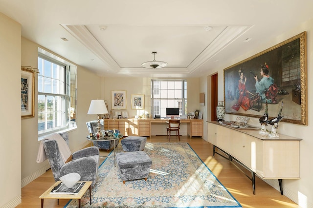 office space with wood finished floors, a tray ceiling, built in study area, and ornamental molding