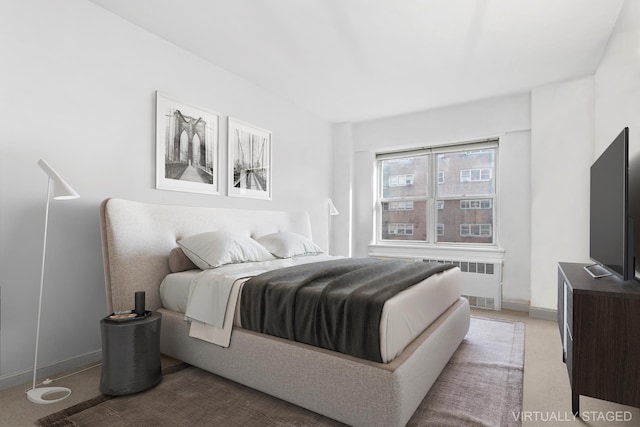 bedroom with radiator heating unit, baseboards, and light carpet