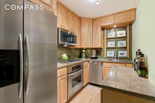 kitchen with backsplash, light brown cabinetry, light wood-type flooring, stainless steel appliances, and a sink