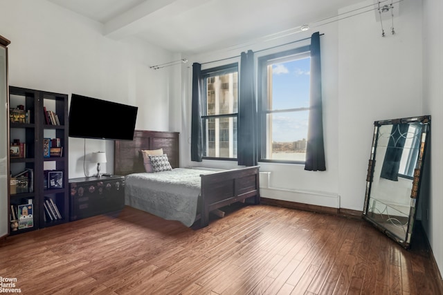 unfurnished bedroom with wood finished floors, beam ceiling, and baseboards