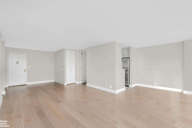 unfurnished living room with light wood-style floors and baseboards