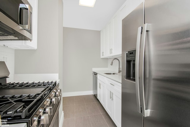 kitchen with tile patterned flooring, white cabinetry, stainless steel appliances, and a sink