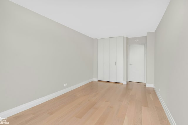 unfurnished bedroom with a closet, light wood-style flooring, and baseboards