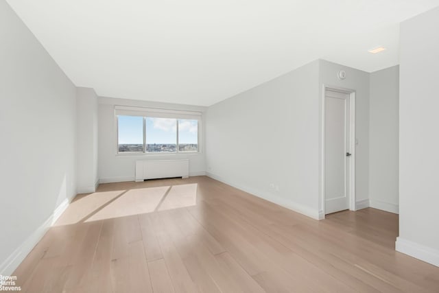 unfurnished room with radiator and light hardwood / wood-style flooring