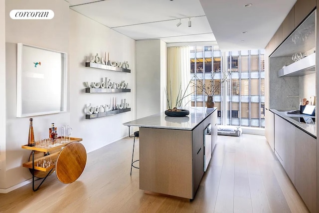 100 E 53rd St Unit 31B, New York City, NY 10022 - kitchen with rail lighting, a breakfast bar, a kitchen island, a wall of windows, and light hardwood / wood-style floors