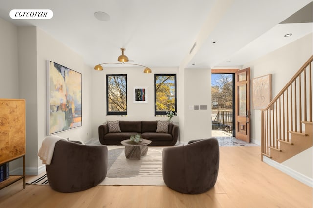 living area featuring visible vents, stairway, baseboards, and wood finished floors