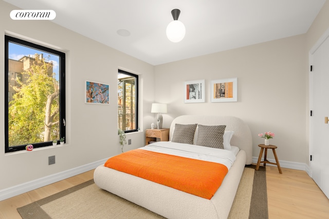 bedroom featuring light wood-style floors, visible vents, and baseboards