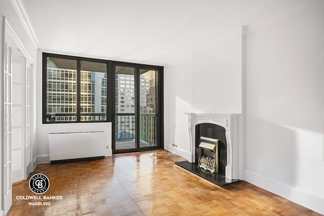 300 E 54th St Unit 10J, New York City, NY 10022 - unfurnished living room with radiator, crown molding, a fireplace with raised hearth, and floor to ceiling windows
