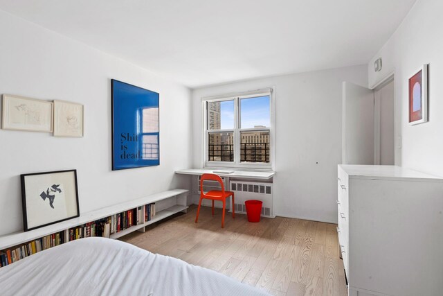 bedroom with radiator heating unit and wood finished floors