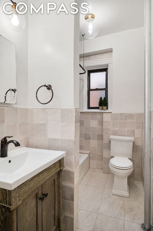 full bathroom with toilet, tile walls, shower / bathtub combination, vanity, and tile patterned flooring