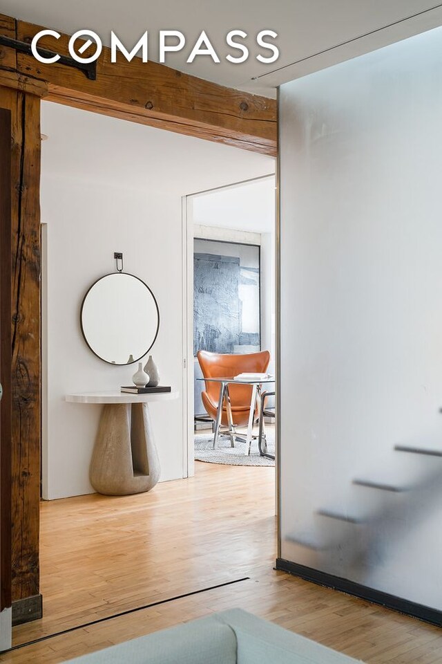 hall featuring beamed ceiling and light wood-type flooring