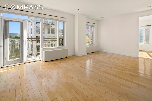 spare room with radiator, a wealth of natural light, and light hardwood / wood-style flooring