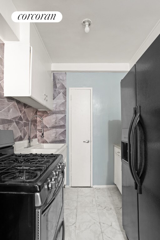 kitchen with crown molding, black refrigerator with ice dispenser, white cabinetry, backsplash, and stainless steel range with gas cooktop