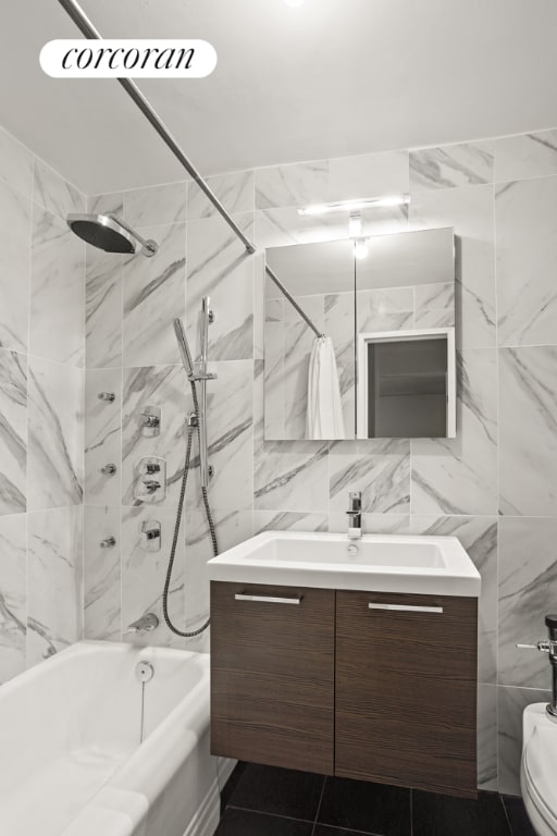 bathroom with tiled shower / bath, vanity, and tile walls