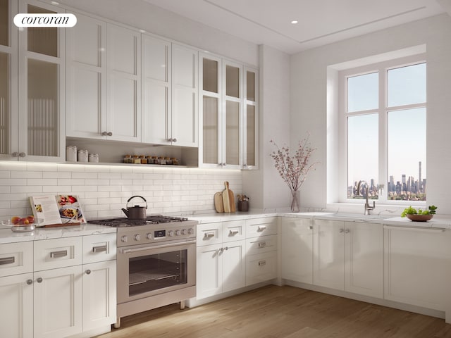 kitchen featuring white cabinetry, stainless steel range with gas cooktop, light wood-style flooring, and a healthy amount of sunlight