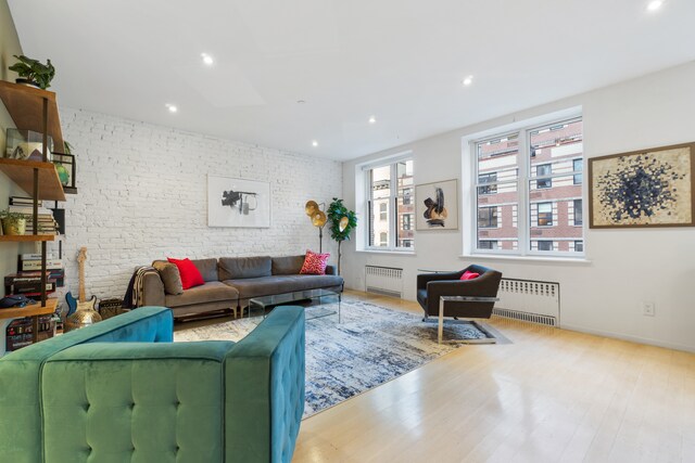 bedroom with brick wall and hardwood / wood-style flooring