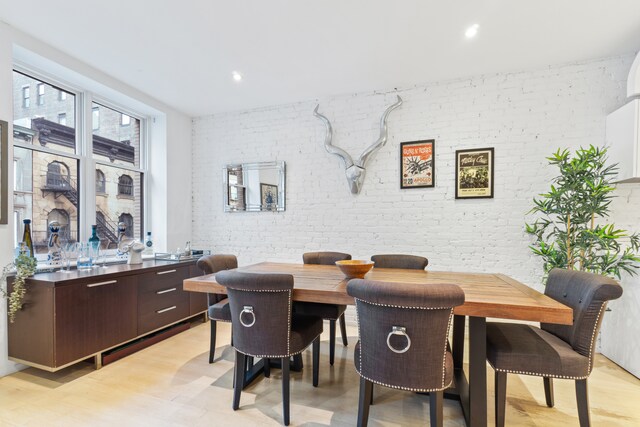 living room featuring brick wall, light hardwood / wood-style flooring, and radiator heating unit